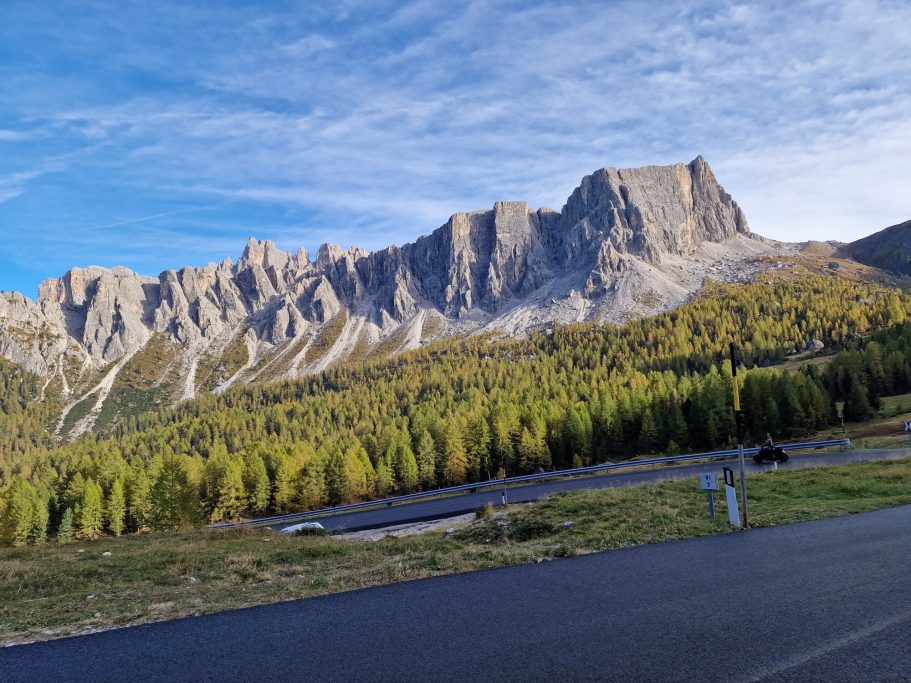Dolomiten Berglandschaft mit hohen Gipfeln und bewaldetem Tal unter blauem Himmel.